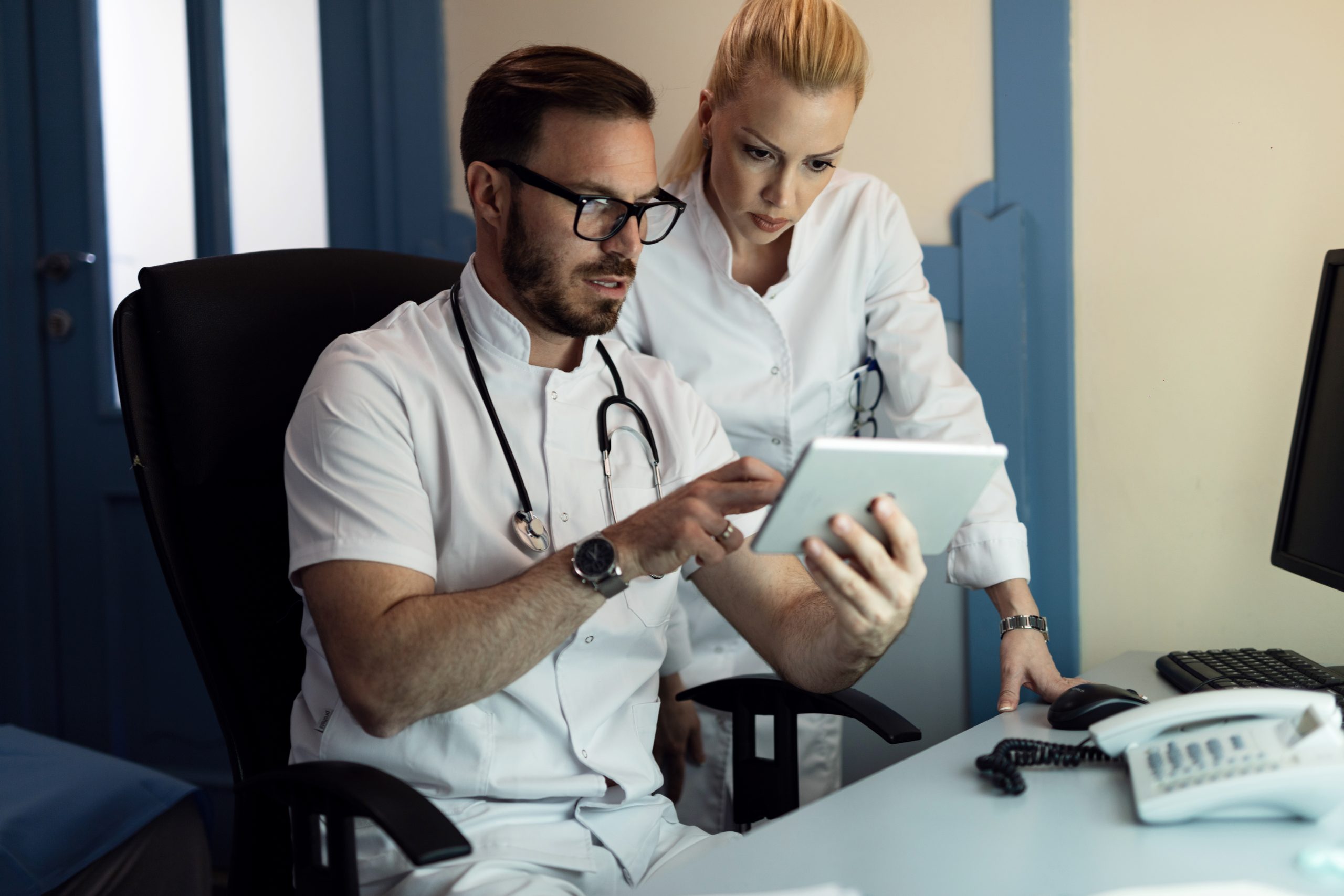 Two doctors analyzing medical reports on touchpad in the hospital. telehealth introduction